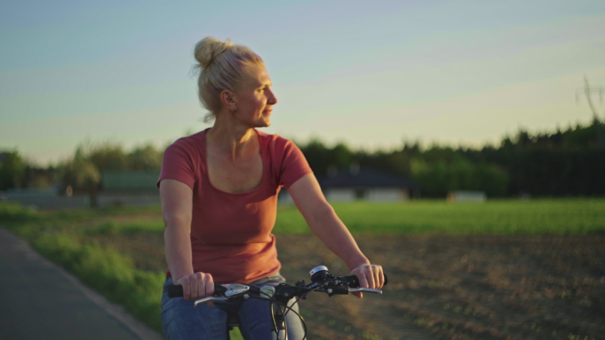 A 50-year-old woman rides a bicycle in the park. A slow motion video of a happy elderly man playing sports and an active lifestyle riding a bicycle. Royalty-Free Stock Footage #1092044149