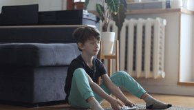 Boy sitting on floor and playing on game console with gamepad. Child excites at game. Fun time at home. Happy boy playing video game with game console