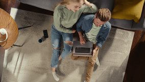 Top View Apartment: Happy Couple Using Laptop in the Stylish Living Room. Looking Up at Camera, Smile. On Couch: Girlfriend and Boyfriend use Computer for Online Shopping, e-business. Zoom Out - Powered by Shutterstock - Get 15% off with code: PIKWIZARD15