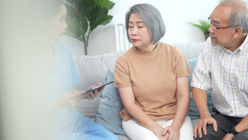 elderly woman patient in nursing home in health insurance service concept, professional physician in uniform using tablet to show a examination result for old female person and support by senior man