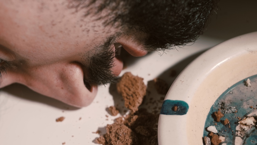 close up on stoned man with his head resting on the table smokes a joint
