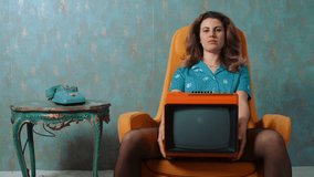 concept, retro - young woman in a retro atmosphere holds an old TV and smiles