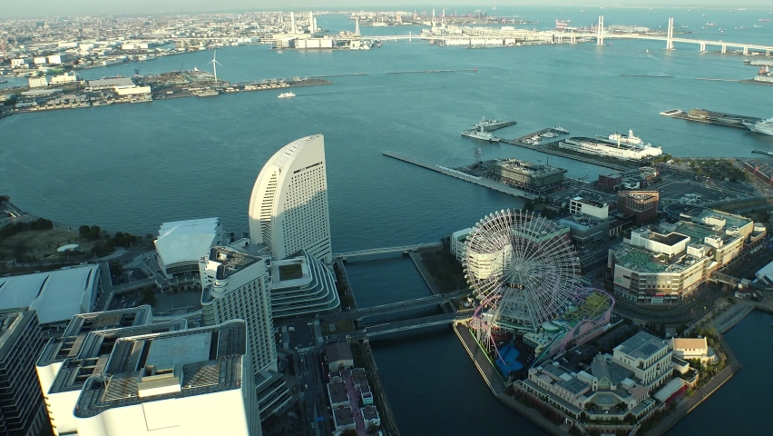 YOKOHAMA, JAPAN : Aerial high angle sunset cityscape of “Minatomirai area“. Seaside urban area. View of buildings and streets around the harbor or port or bay. Long time lapse shot, dusk to night.