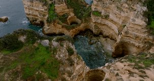 Flying among the rocks which make up the Algarve Coast in Portugal, while panning up the camera