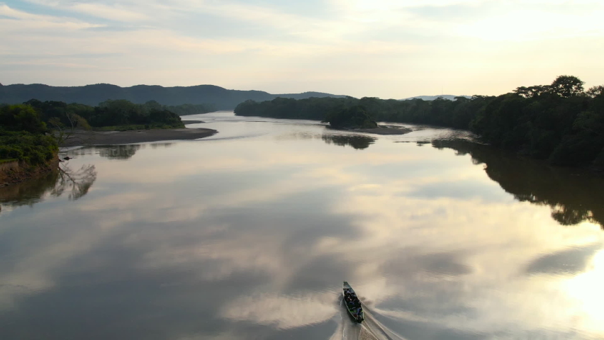 A small boat going up a tranquil river in the Amazon on a perfectly calm afternoon