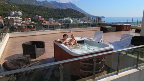 Slowmotion video. Aerial shot of a man and a woman having a good time and relaxing in the hot tub on a rooftop
