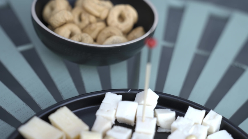 Different types of cheese and walnuts on a rotating plate. An appetizer to expensive alcohol in a bar. Gourmet delicacies.