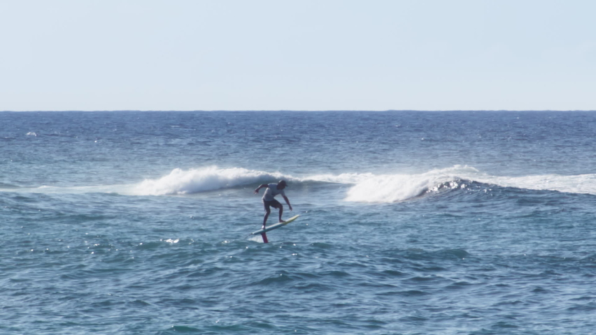 Athletic nan rides a foilboard by using the power of the ocean waves. Water sport activity on Hawaii island. Extreme sport slow motion shot on RED camera. Wake surfer wake boarding on foil board
