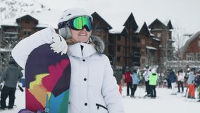 Happy young woman on ski slopes making a picture or video at ski resort in snowy mountains enjoying ski season vacations. Girl having fun in Aspen welcoming friends with wide opened hands, slow motion