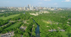 A view of Zikler Park and Barton Springs in downtown Austin, Texas. Flying over Barton Creek towards the city's skyscrapers.