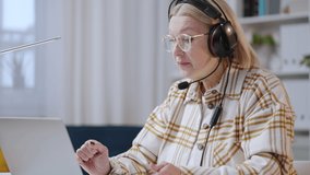 Woman in her 50s in headset talking to clients, call operator, tech support