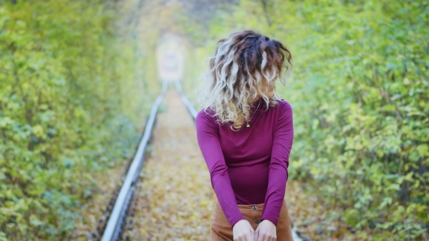 Happy young female tourist spinning in the tunnel of love with autumn leaves, breathing fresh air, hair fluttering in the wind, people freedom concept. happiness.