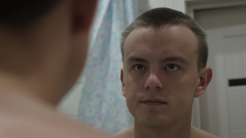 A man cuts his hair with a trimmer on his own, close-up