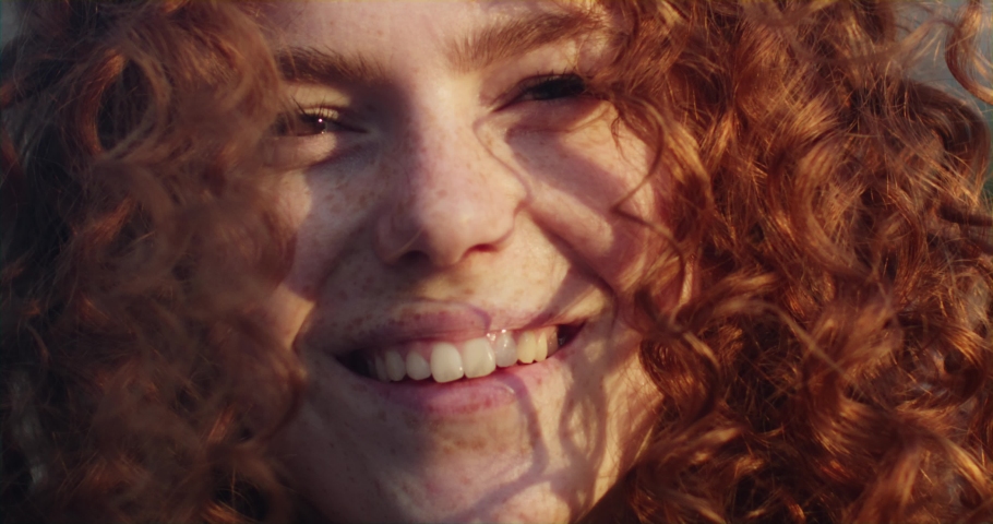 Charming sunshine young smiling woman with red curly hair looking at camera in the city streets at sunlight. Happy portrait face. Slow motion Royalty-Free Stock Footage #1092082011