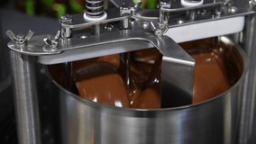 The process of making chocolate confectionery. Stirring machine mixes brown chocolate mass. Small business. Real time video. Selective focus. Small confectionery production theme.