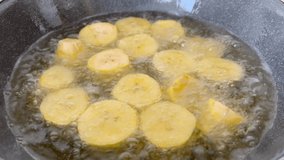 Yellow plantains (patacones) in the frying pan - stock video