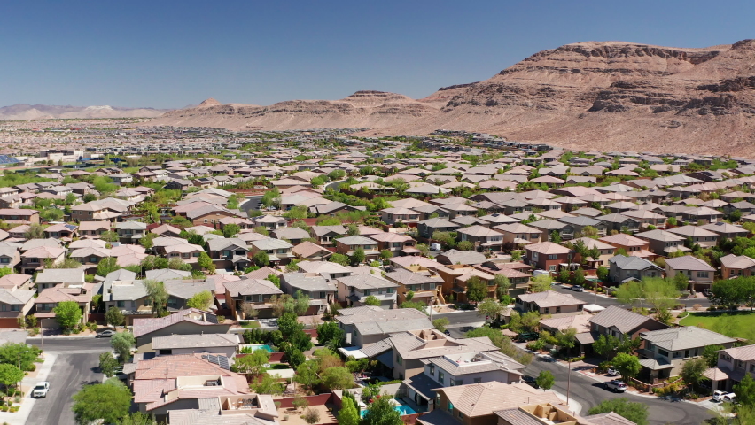 Aerial pullback shot of Las Vegas residential homes with sandstone mountains