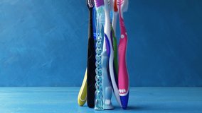 Many multi-colored toothbrushes fall on the table and only one remains standing, then fall again and gather together. 4k raw funny creative loop video with speed ramp effect.