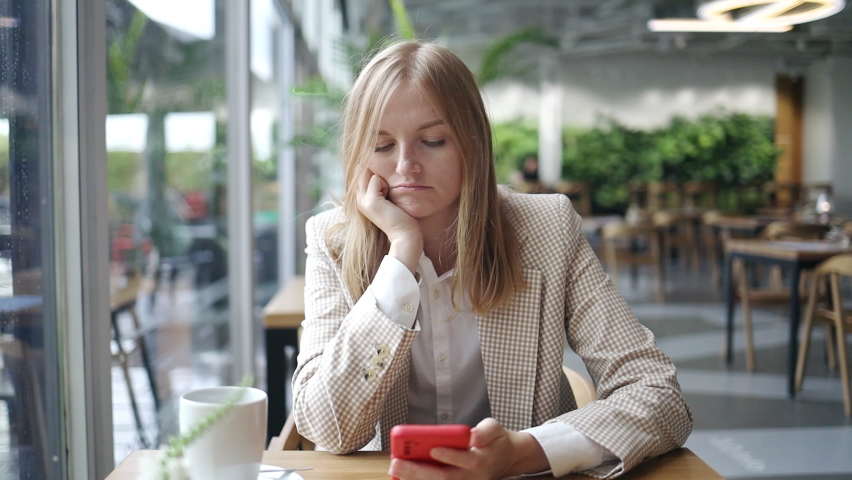 Lonely offended bored sad upset 30s girl, young beautiful frustrated woman in bad mood sitting in cafe with coffee, cell smart phone. High quality 4k footage | Shutterstock HD Video #1092100309