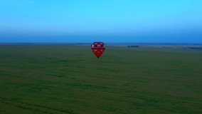 Colorful hot air balloon flying above field with beautiful sky background. Footage from a bird's eye view. Location place Ukraine, Europe. Cinematic drone shot. Filmed UHD 4k video. Beauty of earth.