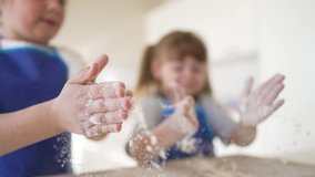 Happy family of cheerful children are preparing dough. Kids in kitchen at table share pizza. Joyful smiles of kids. Dirty children hands knead dough. Kids cooks in an apron at table bake a cake. - Powered by Shutterstock - Get 15% off with code: PIKWIZARD15