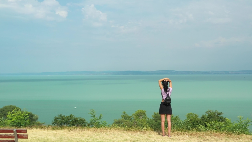 Woman walks on a hill to lake view background summer | Shutterstock HD Video #1092104125
