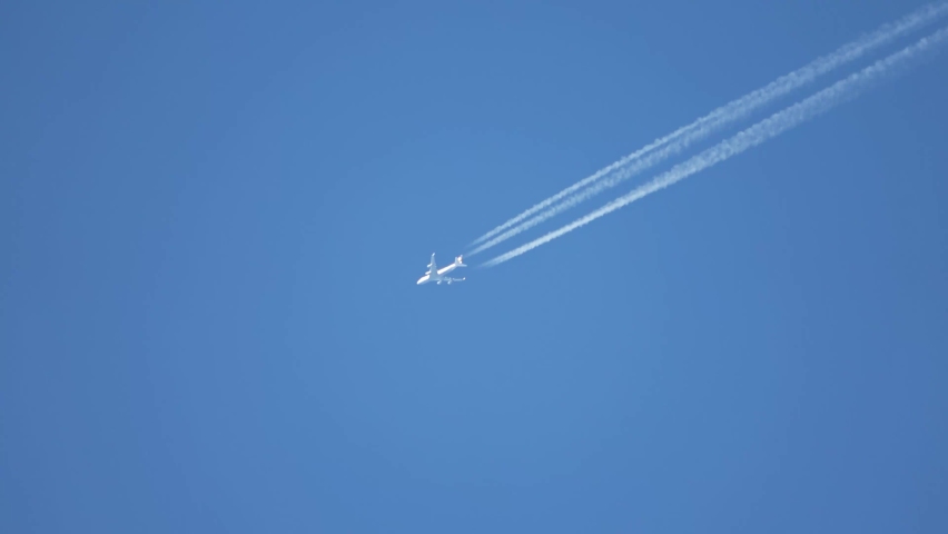 Jet airliner flying high in the sky leaves contrails in the clear blue sky. Royalty-Free Stock Footage #1092114723