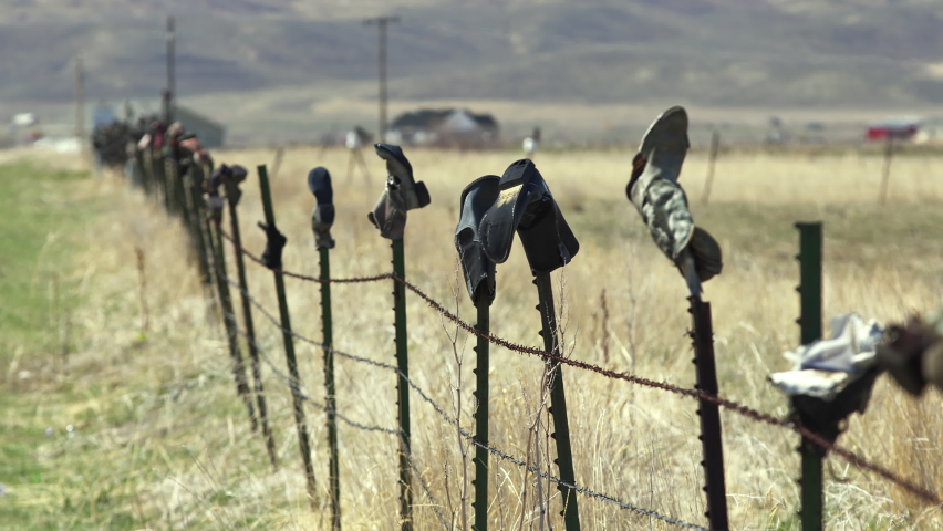 Barbed wire fence with old boots on the top of each post in Malad, Idaho. Royalty-Free Stock Footage #1092119957