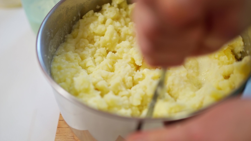female hands with a pusher knead boiled potatoes, mashed potatoes