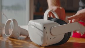 Caucasian male hands picking up virtual reality VR headset from a table at home. Man playing virtual reality games in metaverse. Shot with 2x anamorphic lens - Powered by Shutterstock - Get 15% off with code: PIKWIZARD15