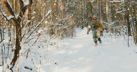Re-enactor Dressed As American Soldier Medic Of USA Infantry Of World War II Fast Running Along Forest Road In Winter Day.