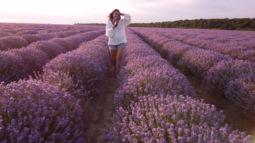 Young woman in white shirt walking in beautiful Lavender field.