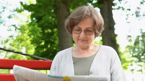 Senior woman reading newspaper, sitting on bench in park. Retirement age - Powered by Shutterstock - Get 15% off with code: PIKWIZARD15