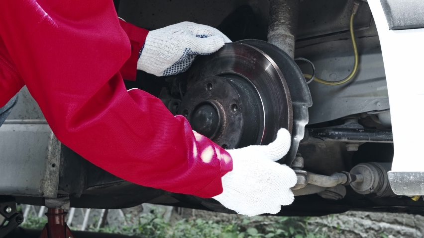 A car mechanic checking weared disc brakes, backing plates and brake pads on a car. Timely maintenance of the car, brake system inspection Royalty-Free Stock Footage #1092140265