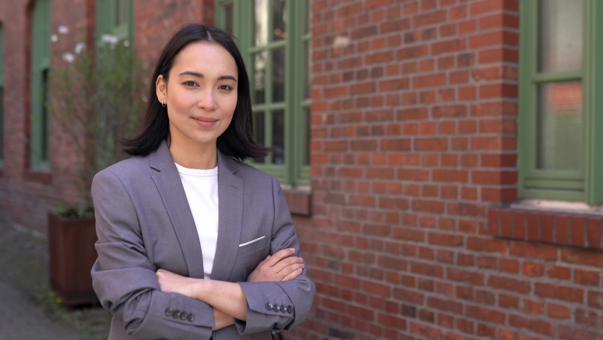 Confident proud young adult Asian business woman professional leader, corporate manager, businesswoman entrepreneur wearing suit looking at camera standing arms crossed outside office, portrait. | Shutterstock HD Video #1092140689