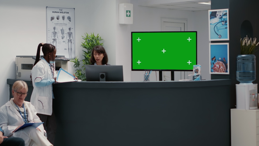 Hospital reception desk with greenscreen on tv monitor in waiting room lobby. Isolated chroma key background with blank copyspace and mockup template on display, medical facility.