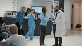 Male physician talking to african american patient about healthcare, showing medical diagnosis results on digital tablet in waiting room lobby at hospital reception. Checkup visit in facility. - Powered by Shutterstock - Get 15% off with code: PIKWIZARD15