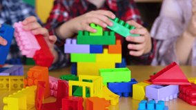 A group of children in a kindergarten building a tower of plastic blocks. Slow motion video.