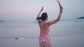 Happy travel live stream blogger in bikini running towards the sea water at sunset 