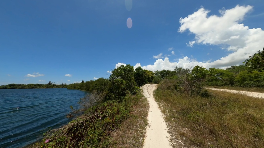 First-person point-of-view twisting, banking and weaving through bike trail next to a lake in a hot sunny day in July at Quiet Waters Park, Deerfield Beach, Florida
