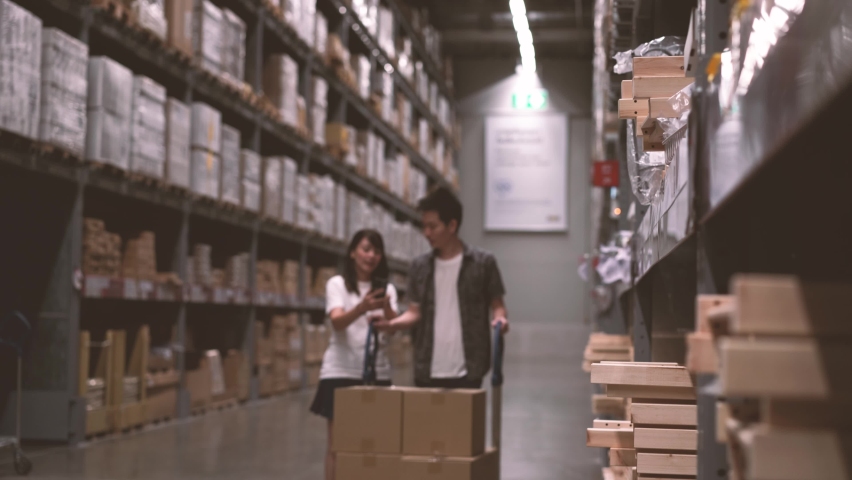 4k resolution.  Couple shopping in large houseware store warehouse with trolley 