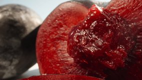 Half of a large red plum, a stone in the plum. a slice of plum on the table under the sun. Dolly slider extreme close-up. Laowa Probe