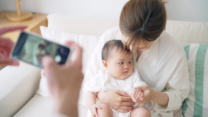 Asian couple shooting photo of their baby with a smart phone. Royalty-Free Stock Footage #1092166769