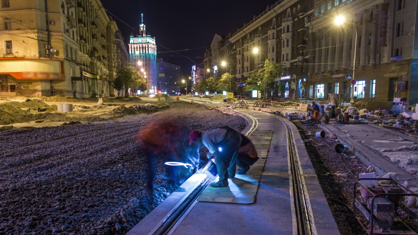 Tram rails at the final stage of their installation and integration into concrete plates on the road night timelapse in the city. Filling by liquid resin for reduction of vibration and noice. The