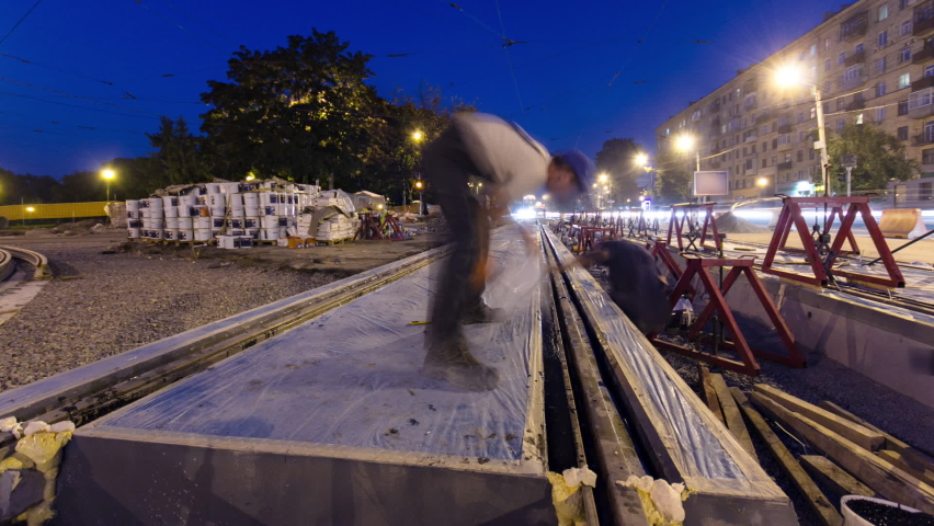 Tram rails at the final stage of their installation and integration into concrete plates on the road night timelapse hyperlapse. Filling by liquid resin for reduction of vibration and noice. The