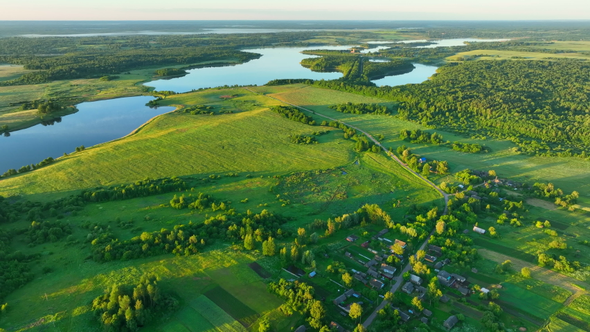 Rural landscape with country houses. Lake in countryside in Foggy dawn, aerial view. Lake in morning mist sunrise. Drone shot flying over Country House in rural. Bird