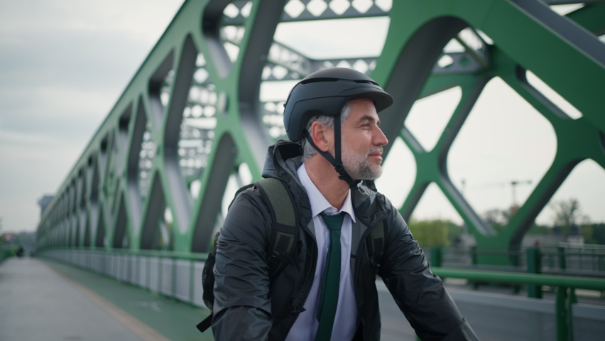 Businessman commuter on the way to work, riding bike onver bridge, sustainable lifestyle concept.