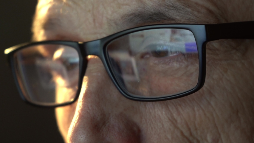 Close-up of the focused eyes of a businessman wearing computer glasses, looking at a reflective PC screen Royalty-Free Stock Footage #1092176799