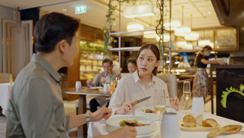 Asian couple having dinner at an upscale restaurant. They enjoy dinner and champagne in this night. Royalty-Free Stock Footage #1092180233