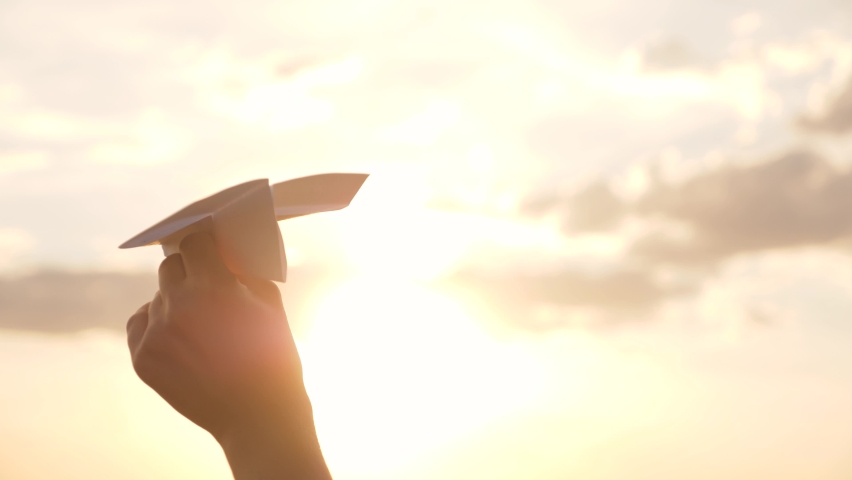 Silhouette of paper airplane in child's hand against background of sunset sky. Take off dream toy plane. Child's hand holds paper airplane in sky. Child playing in toy plane silhouette, child's dream. Royalty-Free Stock Footage #1092187165